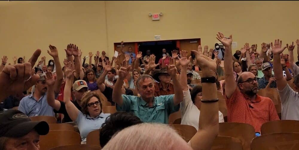 Everyone raised their hands when asked if they supported the pump project. Photo by David Day