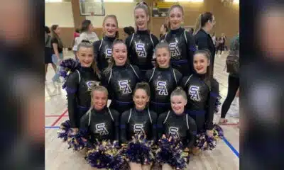 Flashettes dance team members posing in cheer outfits with pom-poms, celebrating the — Flashettes dance team Nationals bid