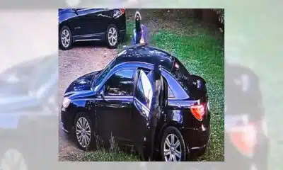 A black car with an open door parked on grass, with a person standing nearby, rela — child injured in Jackson park robbery