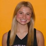 Smiling young female basketball player in a black jersey against a bright orange background. — Larsen