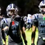 Three Port Gibson football players in black uniforms celebrate on the field after a play during the s — Port Gibson season