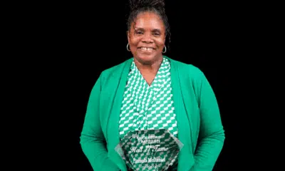 Pamela McDaniel smiling while holding an award, wearing a green cardigan and patterned top.