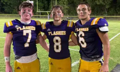 Three St. Aloysius Junior High football players celebrating after a game, wearing purple and gold uniforms, with a — 42-8
