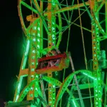 Brightly lit Ferris wheel at night, showcasing vibrant green lights at the Yazoo Fair.