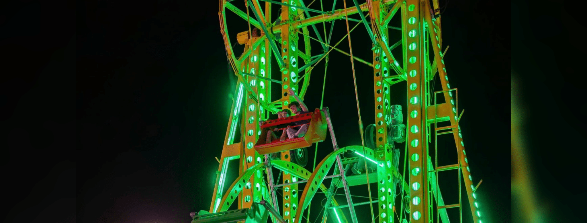 Brightly lit Ferris wheel at night, showcasing vibrant green lights at the Yazoo Fair.