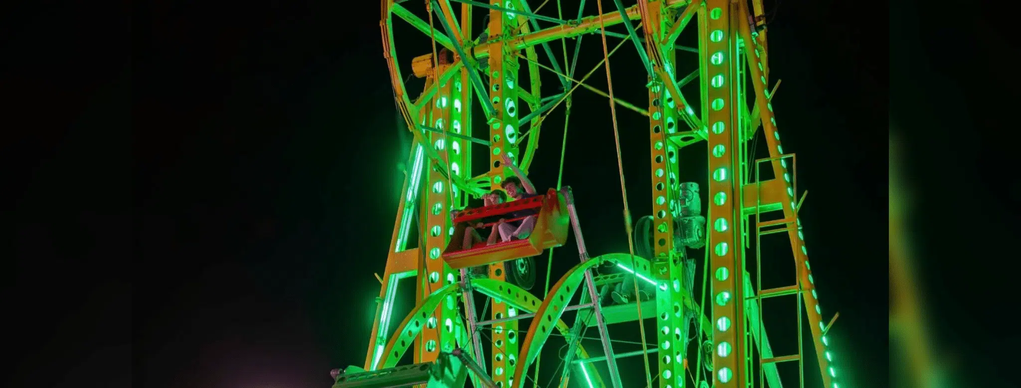 Brightly lit Ferris wheel at night, showcasing vibrant green lights at the Yazoo Fair.