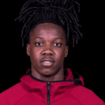 Michael Hall, a young athlete with long dark hair, wearing a red jacket, looking directly at the camera.