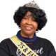 A woman wearing a tiara and sash celebrating her 75th birthday, smiling warmly. — Roberta Anderson