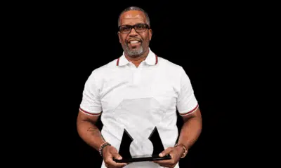 Kevin Dent holding an award, smiling, wearing a white polo shirt with glasses.