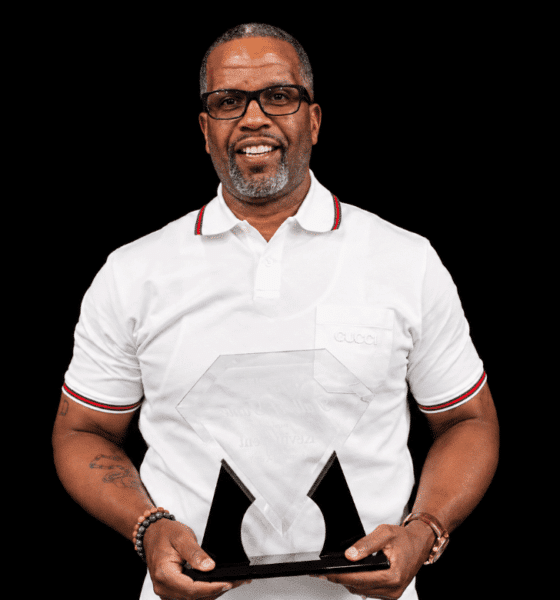 Kevin Dent holding an award, smiling, wearing a white polo shirt with glasses.