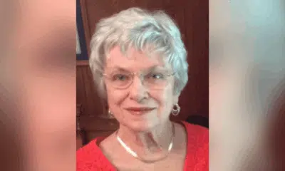 A smiling elderly woman with short gray hair and glasses, wearing a red top, exuding warmth a — Patricia Fairchild Oglesby