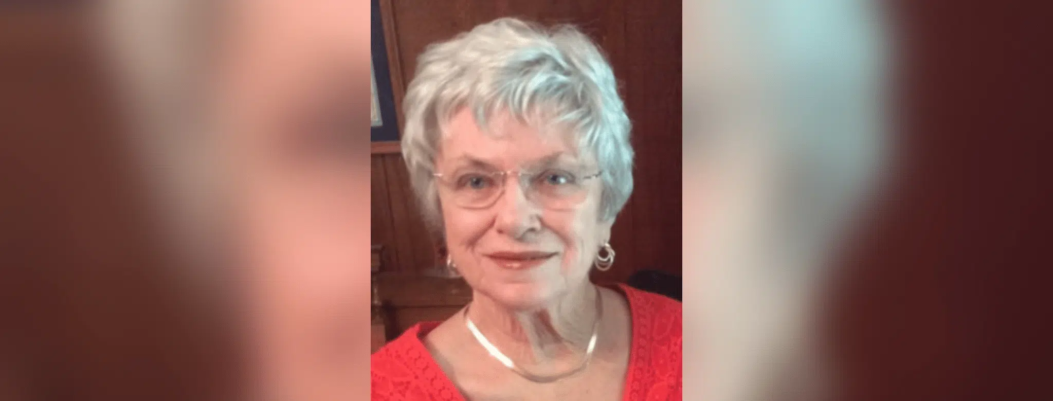 A smiling elderly woman with short gray hair and glasses, wearing a red top, exuding warmth a — Patricia Fairchild Oglesby