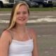 A young woman with long blonde hair smiles while sitting outdoors, wearing a white tank top. — Avery Read Carroll