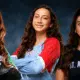 Three volleyball players from Vicksburg, Warren Central, and St. Aloysius pose confidently in their team jerseys.