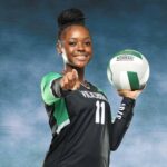 A volleyball player in a black uniform holds a volleyball and points confidently at the camera, sho — Vicksburg volleyball