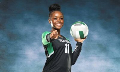 A volleyball player in a black uniform holds a volleyball and points confidently at the camera, sho — Vicksburg volleyball