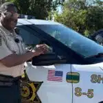 John Williams, Deputy of the Year, stands next to a sheriff's vehicle, smiling and posing for the camera.