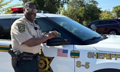 John Williams, Deputy of the Year, stands next to a sheriff's vehicle, smiling and posing for the camera.