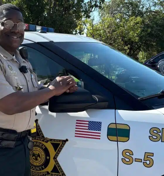 John Williams, Deputy of the Year, stands next to a sheriff's vehicle, smiling and posing for the camera.
