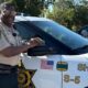 John Williams, Deputy of the Year, stands next to a sheriff's vehicle, smiling and posing for the camera.