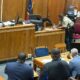 A courtroom scene with a judge, a sheriff's deputy, and several individuals seated at a table, discussing — Second chance