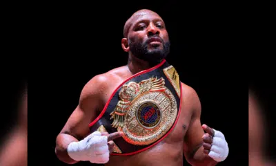 Martin Trey Brown, a muscular fighter, poses confidently with a championship belt in a boxing ring, showcasing his MMA suc…