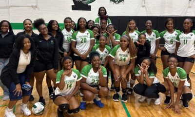 Vicksburg High School volleyball team poses together in their gym after a match, celebrating their victory.