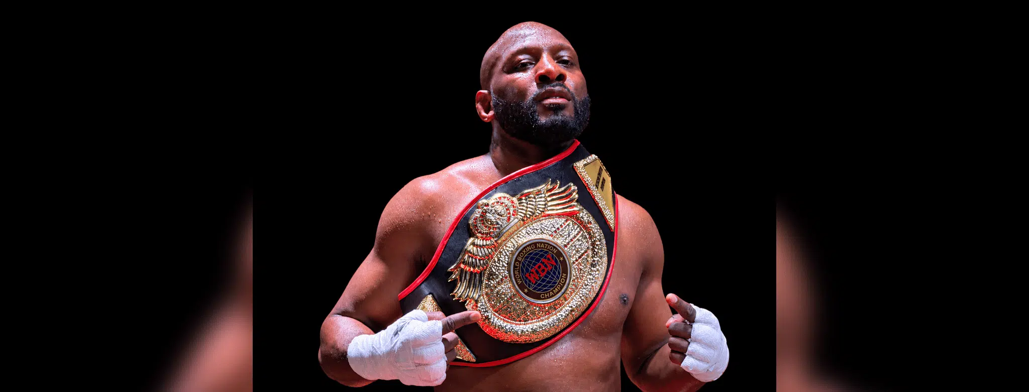 Martin Trey Brown, a muscular fighter, poses confidently with a championship belt in a boxing ring, showcasing his MMA suc…