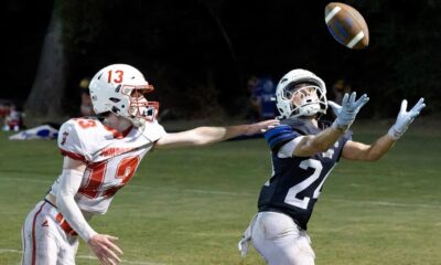 A football player in a blue jersey reaches for the ball while an opponent in a red jersey attempts to defend. — 58-32