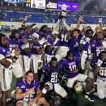 Alcorn football team celebrates victory at the Southern Heritage Classic, holding a trophy and posing for the camera.