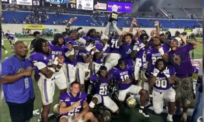 Alcorn football team celebrates victory at the Southern Heritage Classic, holding a trophy and posing for the camera.