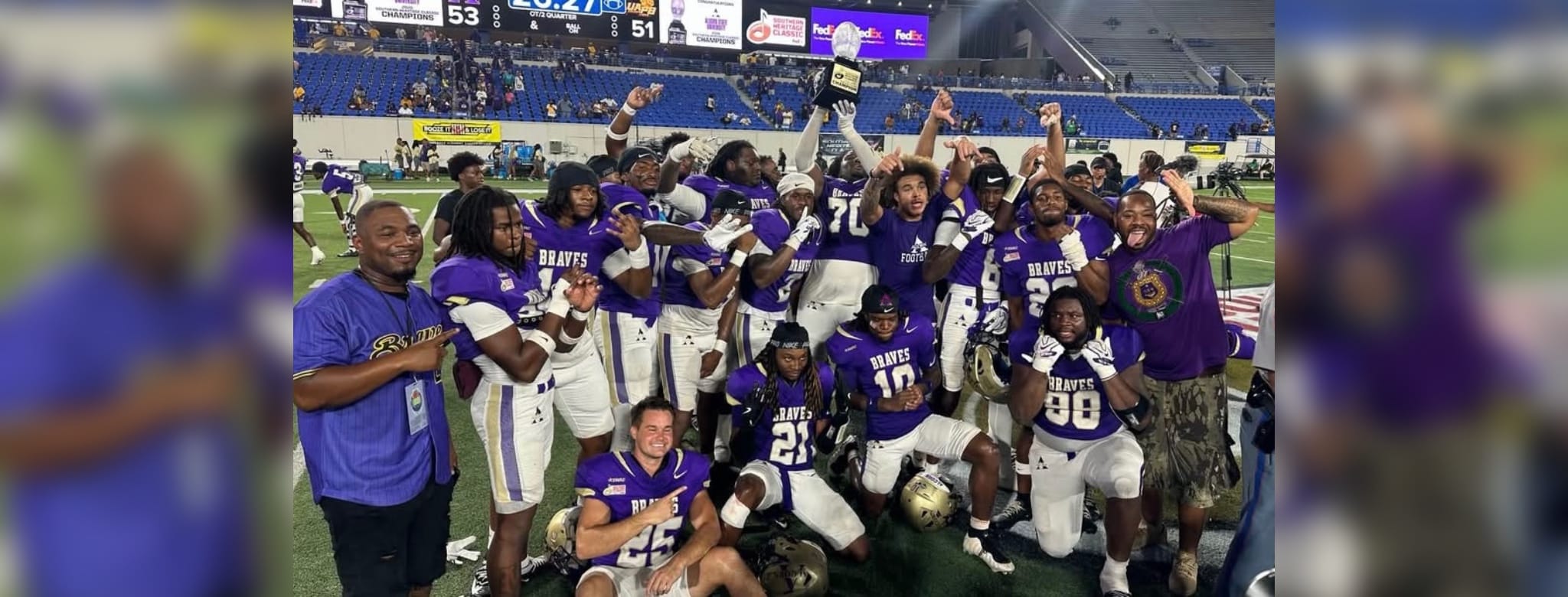Alcorn football team celebrates victory at the Southern Heritage Classic, holding a trophy and posing for the camera.