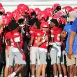 WCJHS football team in red uniforms celebrating with their coach a — WCJHS made a comeback to defeat Madison Central 26-14