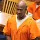 A man in an orange prison jumpsuit stands in a courtroom, looking serious, with other individuals se — Failure to register