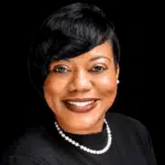 Rashandra Laws, a nurse practitioner, smiling in a professional setting with a black background.