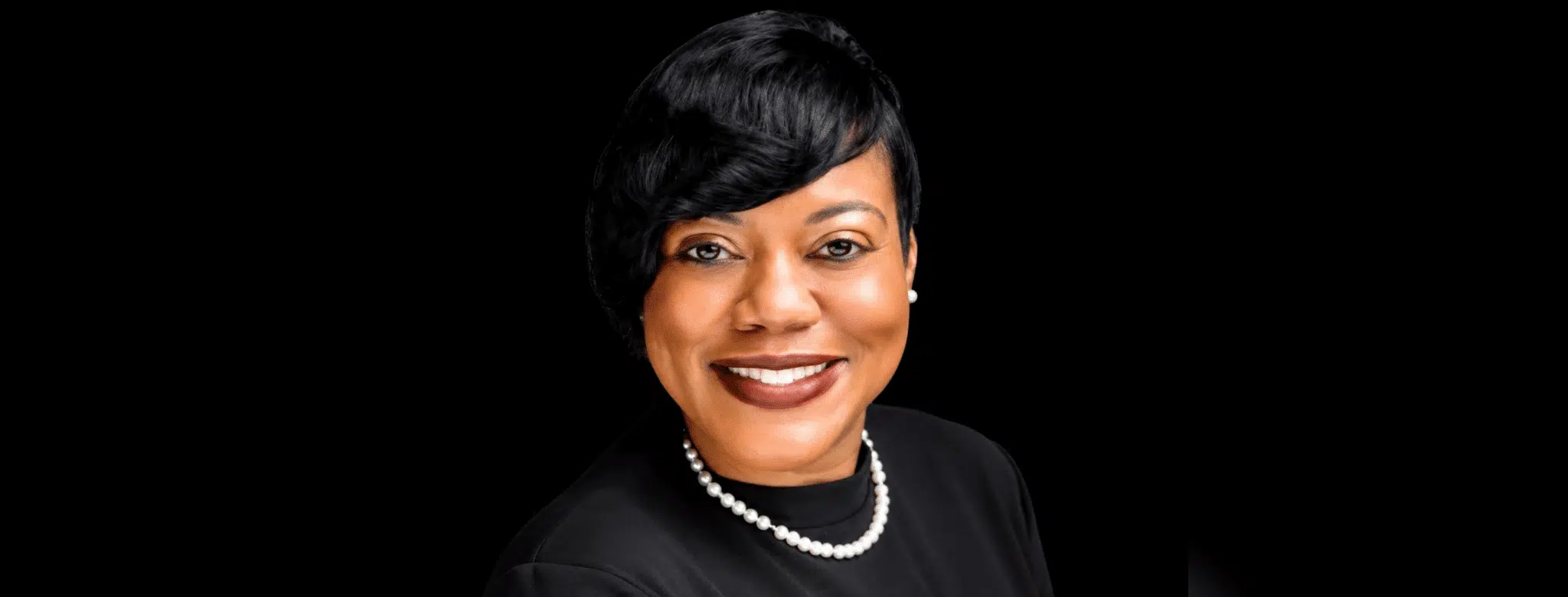 Rashandra Laws, a nurse practitioner, smiling in a professional setting with a black background.