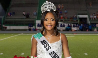 Lauren Gibbs wearing a crown and sash, smiling while holding flowers on a football field.