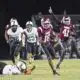Hinds CC football player running with the ball while defenders chase during a game, celebrating a touchdown. — 52-28