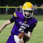 A St. Aloysius quarterback in a purple jersey runs with the football during a — Flashes defeated Manchester Academy 49-14