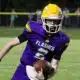 A St. Aloysius quarterback in a purple jersey runs with the football during a — Flashes defeated Manchester Academy 49-14