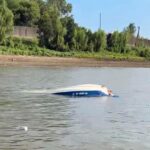 Capsized ski boat on the river with visible damage and water surrounding it. — Barge