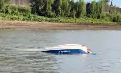 Capsized ski boat on the river with visible damage and water surrounding it. — Barge