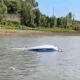 Capsized ski boat on the river with visible damage and water surrounding it. — Barge