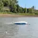 Capsized ski boat on the river with visible damage and water surrounding it. — Barge