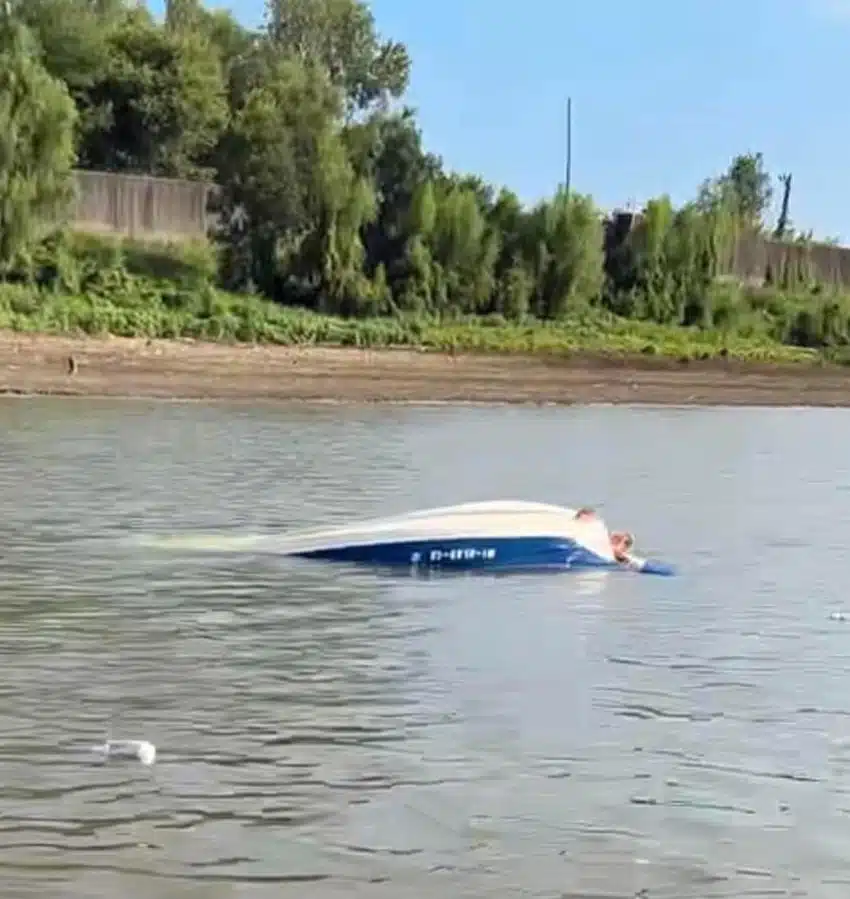 Capsized ski boat on the river with visible damage and water surrounding it. — Barge