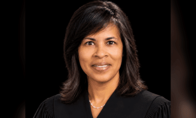 Judge Vicki Barnes in judicial robes, smiling against a dark background.