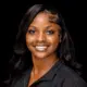 Ty’Kerria Henderson, a family medicine provider, smiles confidently in a professional setting.