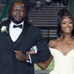 A smiling young woman in a white gown is escorted by a man in a tuxedo at homecoming, part of — 1 million views homecoming