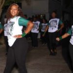 Gator girls 50 years: dancers in matching shirts perform outdoors, led by a woman posing with one hand on her hip.