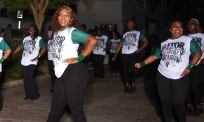 Gator girls 50 years: dancers in matching shirts perform outdoors, led by a woman posing with one hand on her hip.